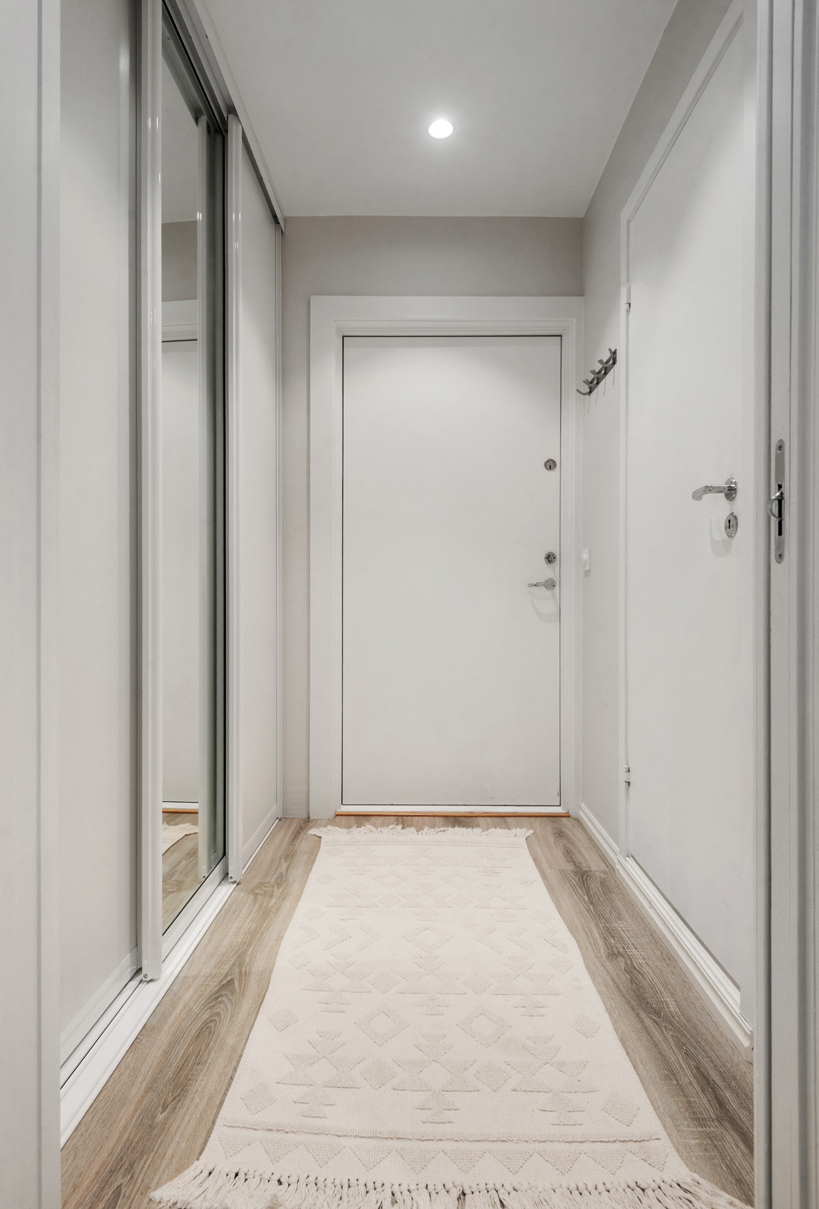 Man ankommer leiligheten i en innbydende entré med lyse flater og downlights i himlingen Galleribilde