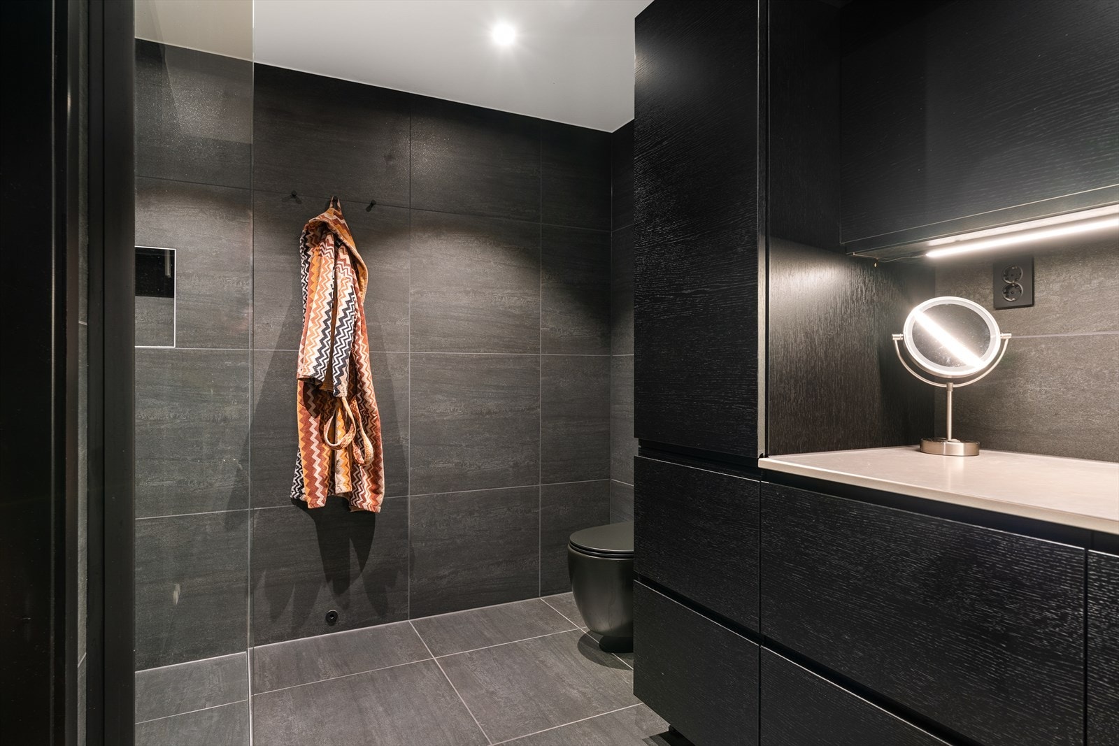 Rommet innehar en standard som virkelig overgår forventningene til et vaskerom. Nydelig 60x60 flis på gulv/vegg, stilrene skapfronter, underlimt servant og vegghengt wc i sort uttførelse. Galleribilde