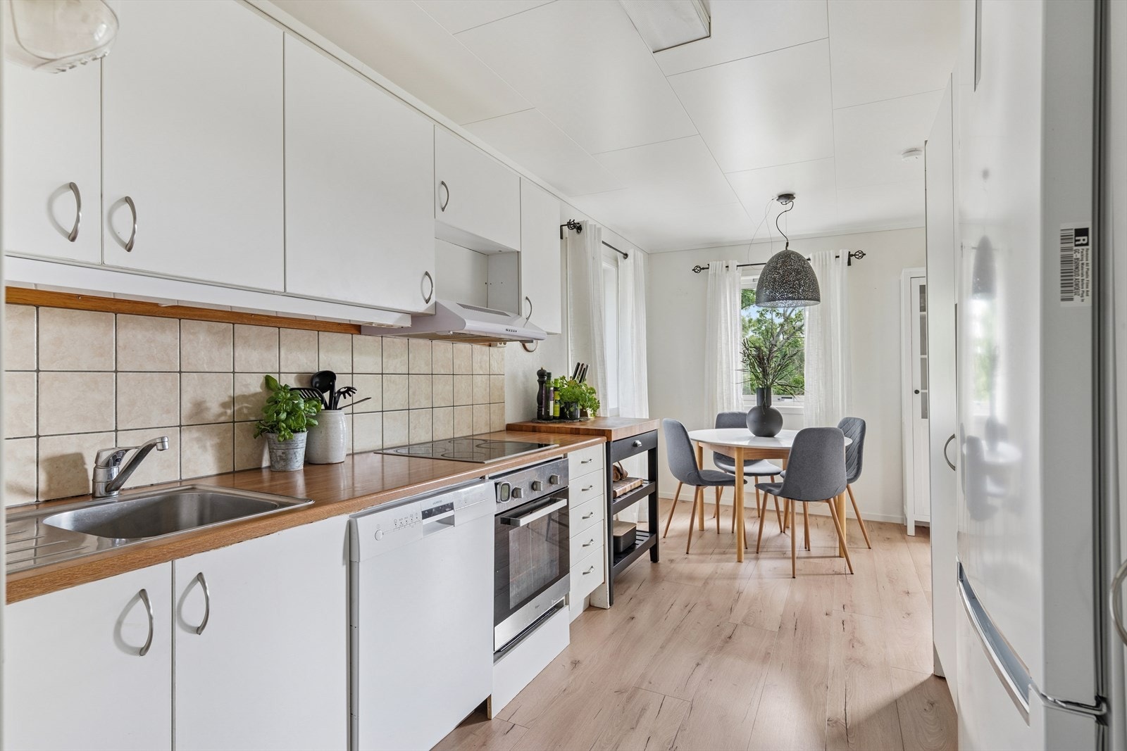 Praktisk kjøkken med hvite, glatte fronter og rikelig med oppbevaringsplass Galleribilde