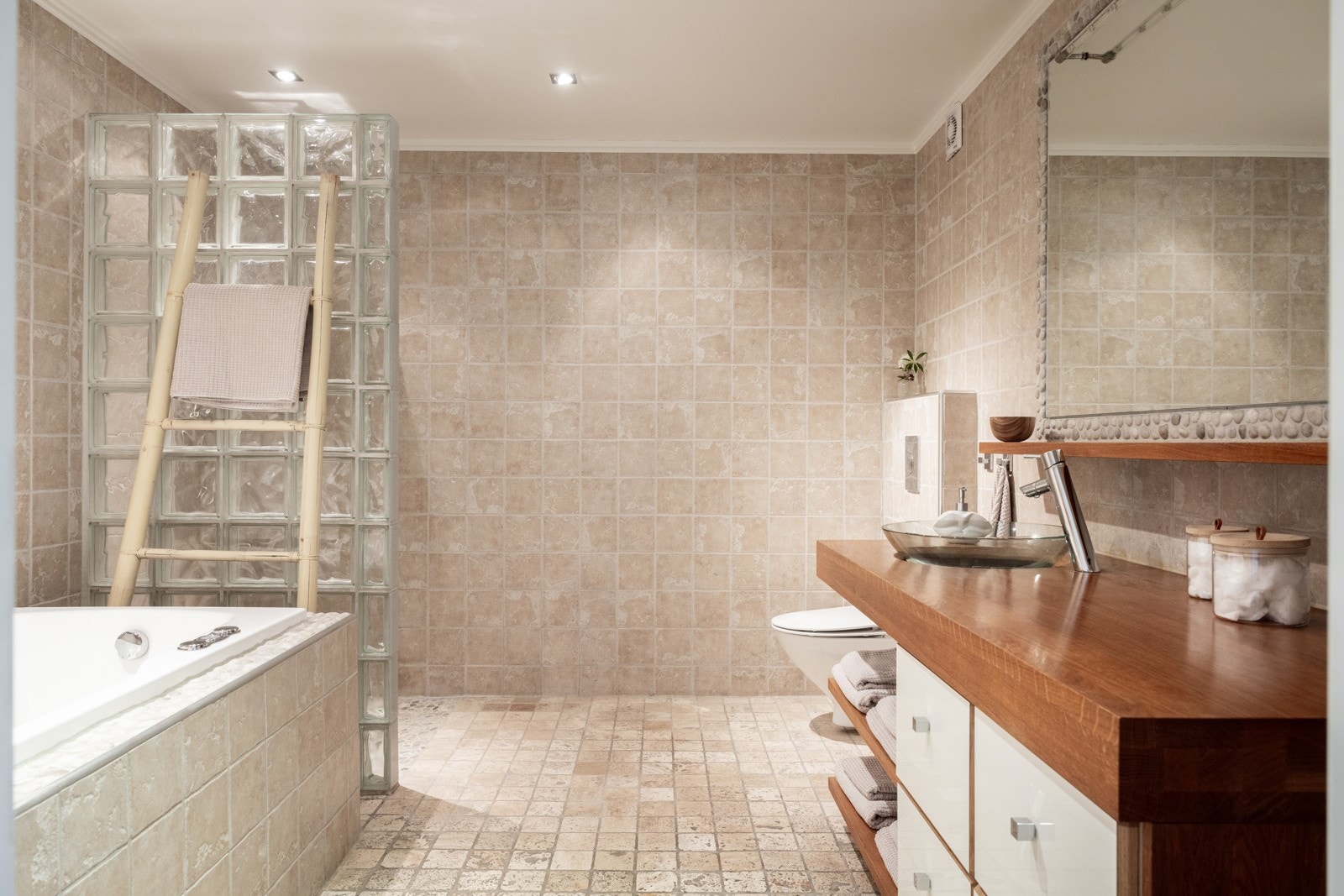 Badet fremstår som moderne og funksjonelt, med helhetlig flislegging på både gulv og vegger i nøytrale, varme toner og marmor på gulv. Galleribilde