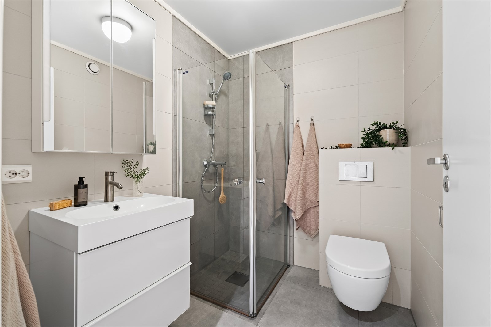 Her finner du vegghengt toalett, servant med romslige underskuffer, speilskap og dusj med innfellbare glassvegger. Et perfekt gjestebad! Galleribilde