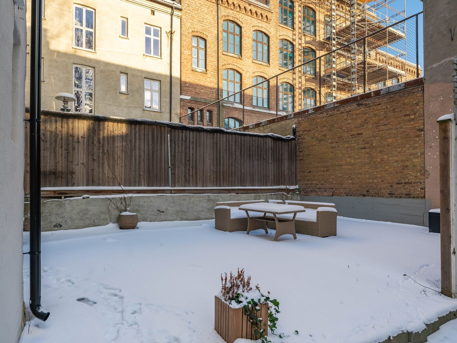 Uteområdet har et sitteområde med bord og stoler, omgitt av murvegger. Galleribilde