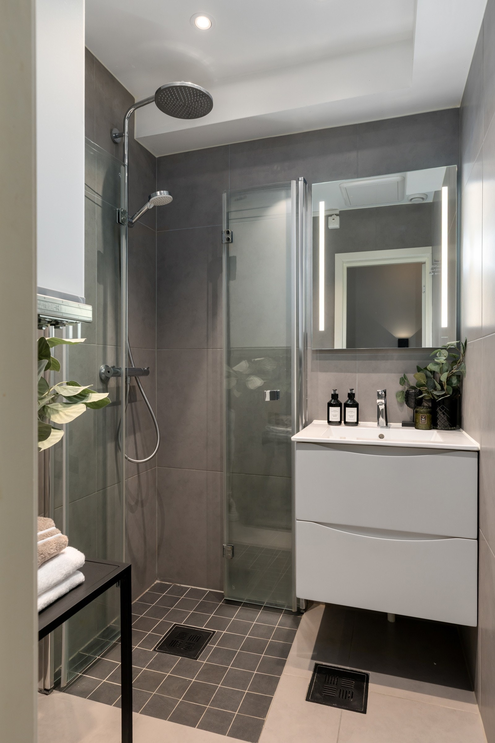 Det er varmekabler i gulvet og downlights i taket. Innredningen består av en heldekkende servant på hvit skuffeseksjon, speil med integrert belysning, samt foldedører i glass, regnfallsdusj og hånddusj i dusjhjørnet. Opplegg for vaskemaskin. Galleribilde