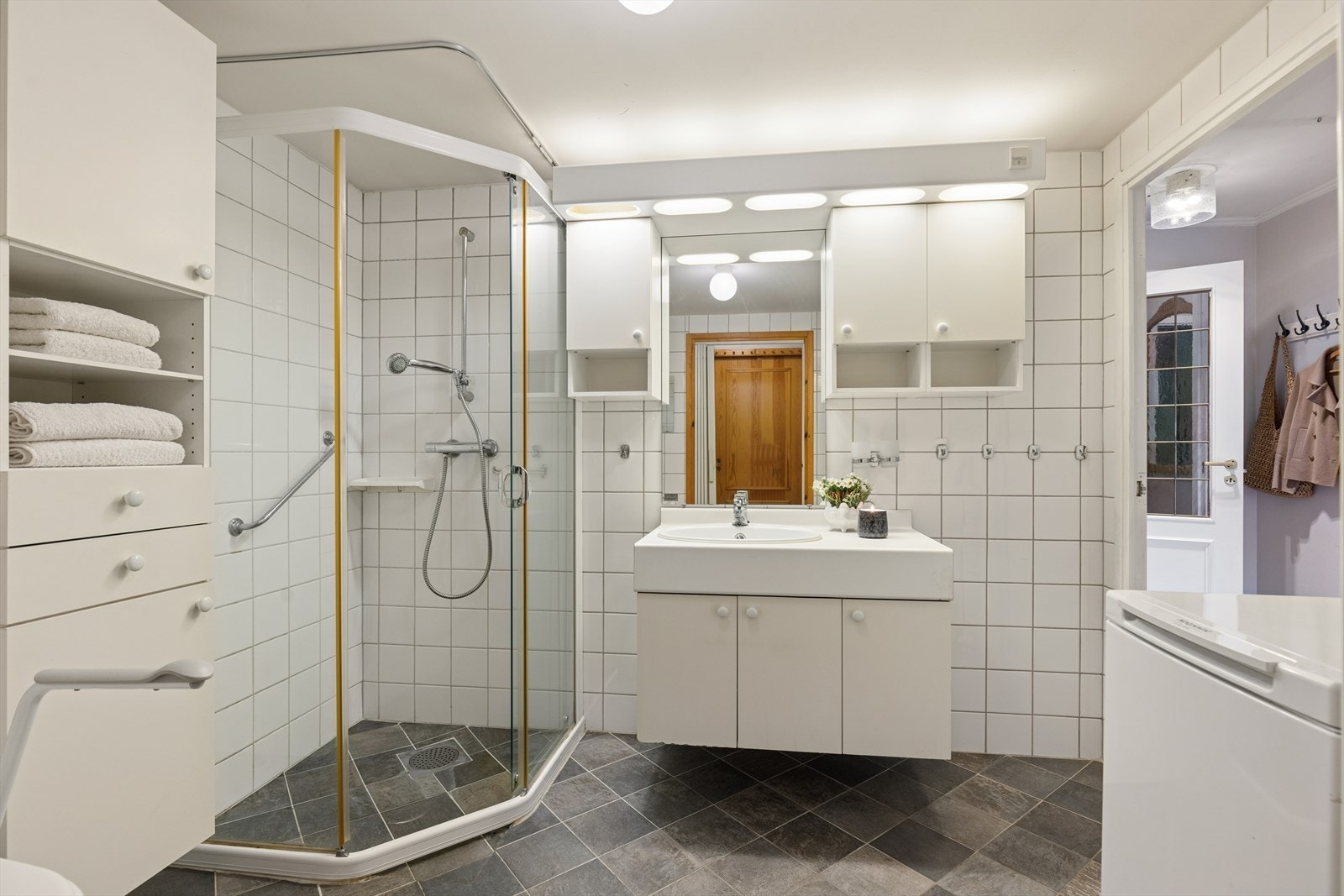 Badet er utstyrt med servant, vegghengt toalett, dusjhjørne og opplegg for vaskemaskin. Galleribilde