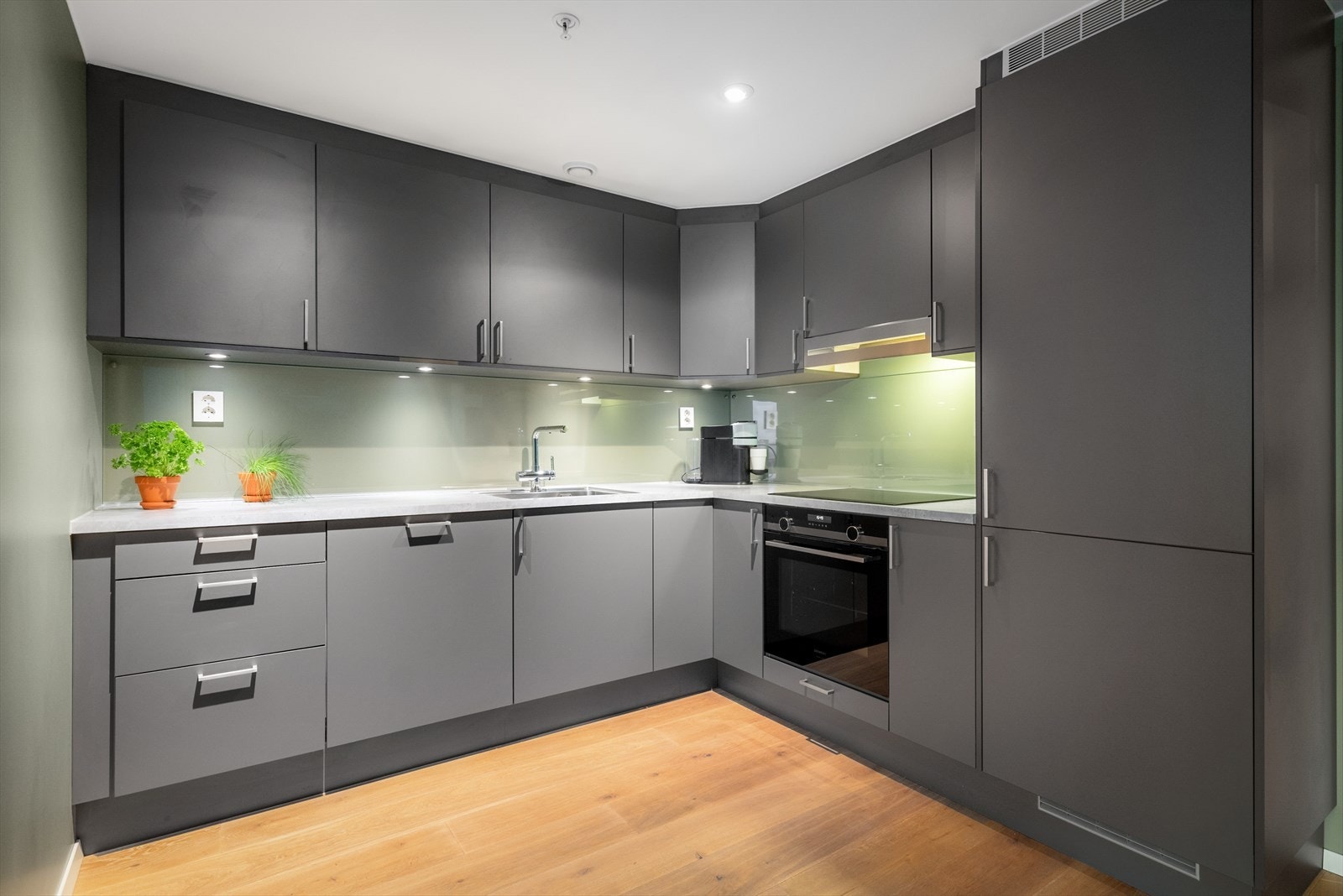 Kjøkkeninnredning med glatte, folierte fronter og godt med skapplass. Galleribilde