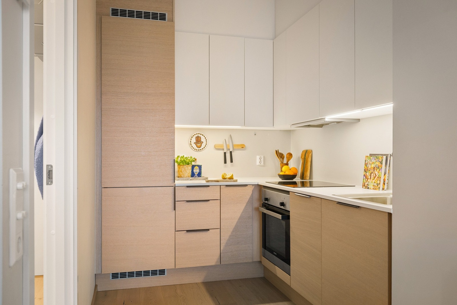 Legg merke til at overskapene er lyse og går nærmest i ett med overflatene. Derfor oppleves ikke kjøkkenet dominerende mot stua. Galleribilde