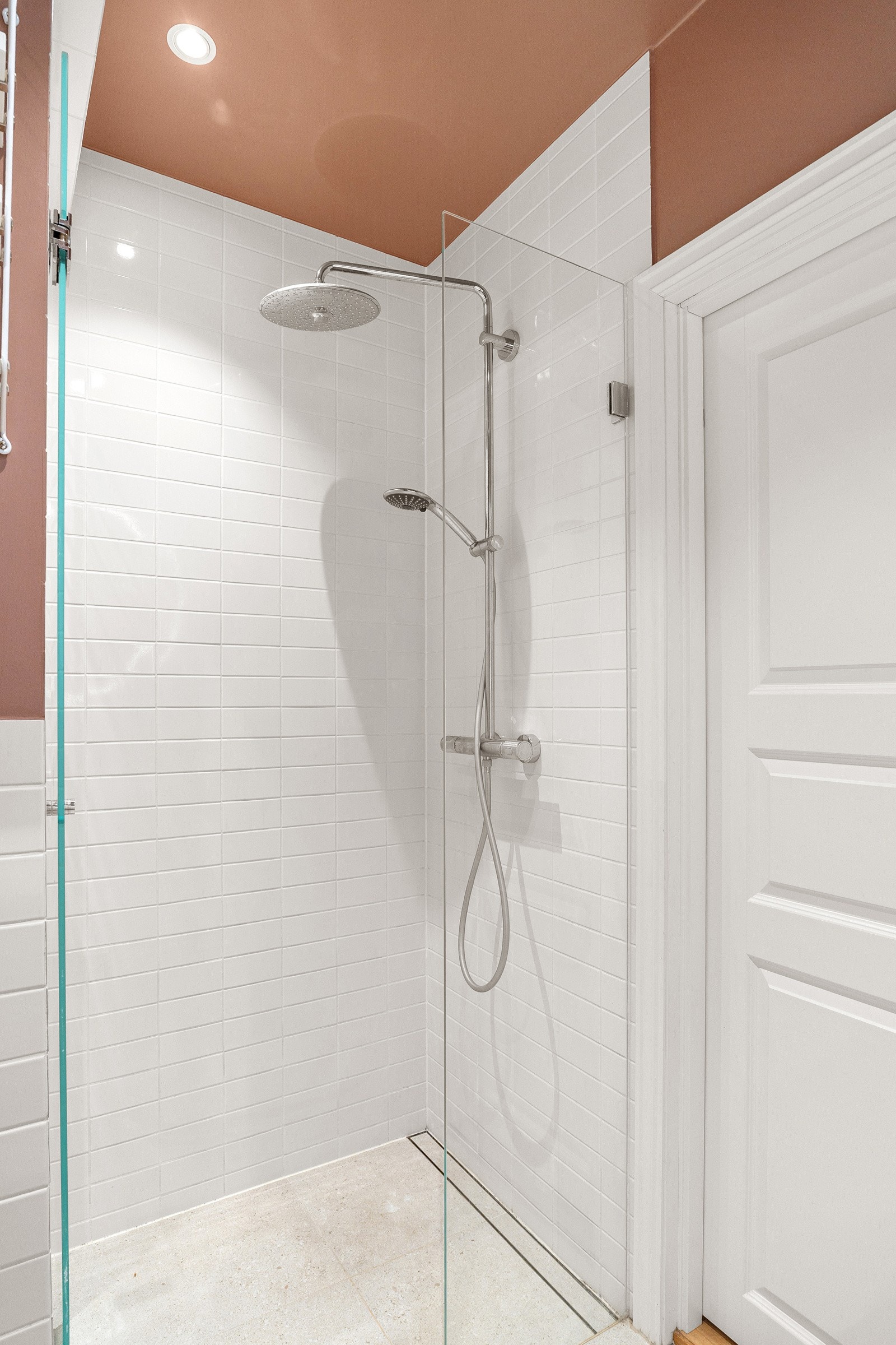 Rommet inneholder varmekabler, servantskap med speil og lys over og dusjhjørne med glassvegg og regnfallsdusj. Galleribilde