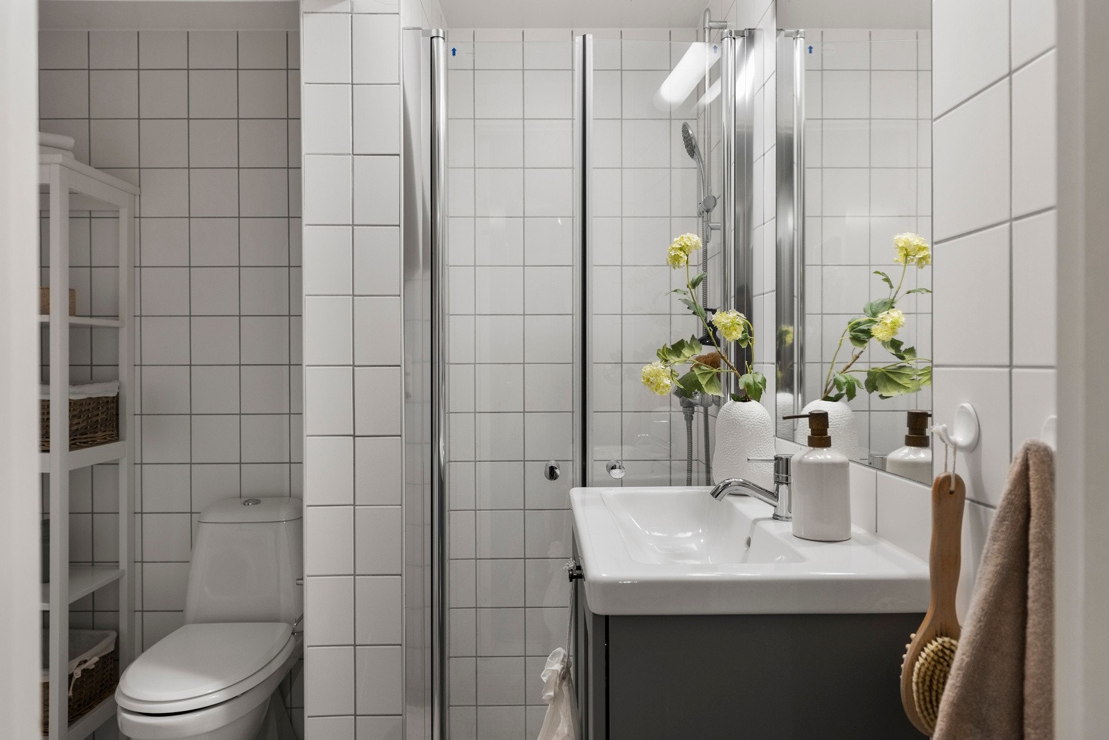 Flislagt bad med varmekabler, dusjhjørne, veggmontert servantskap og gulvstående toalett samt opplegg for vaskemaskin Galleribilde