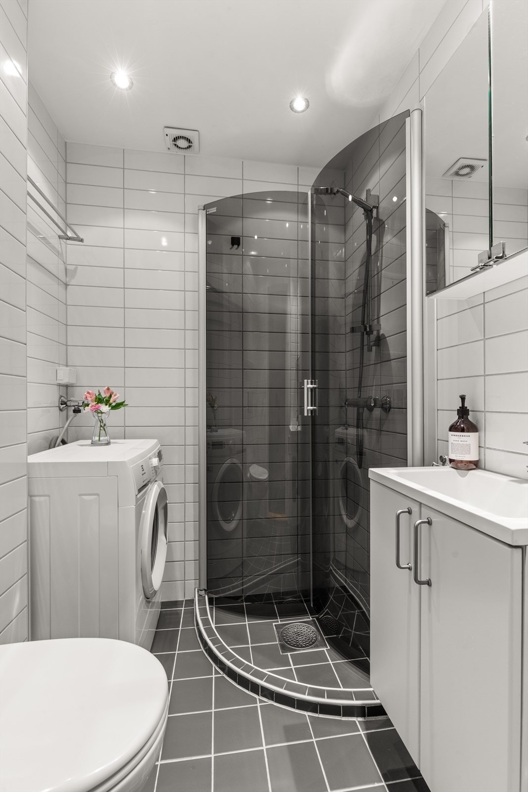 Badet er innredet med dusjhjørne med glassdører, servant og toalett. Det er både plass og opplegg for vaskemaskin og tørketrommel. Galleribilde