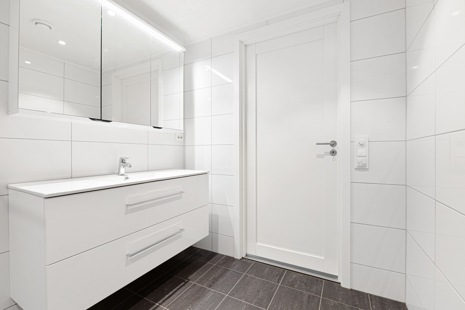 Badet er innredet med dusjnisje med innfellbare glassvegger, toalett og baderomsinnrending med servant. Galleribilde