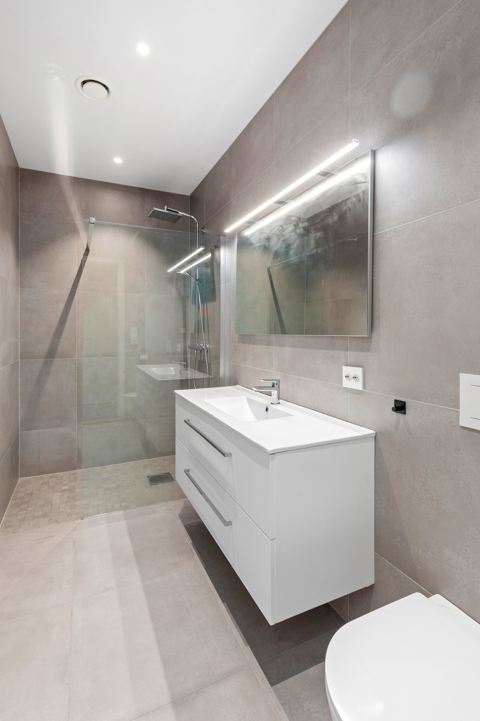 Moderne og stilrent bad med fliser på både gulv og vegger Galleribilde