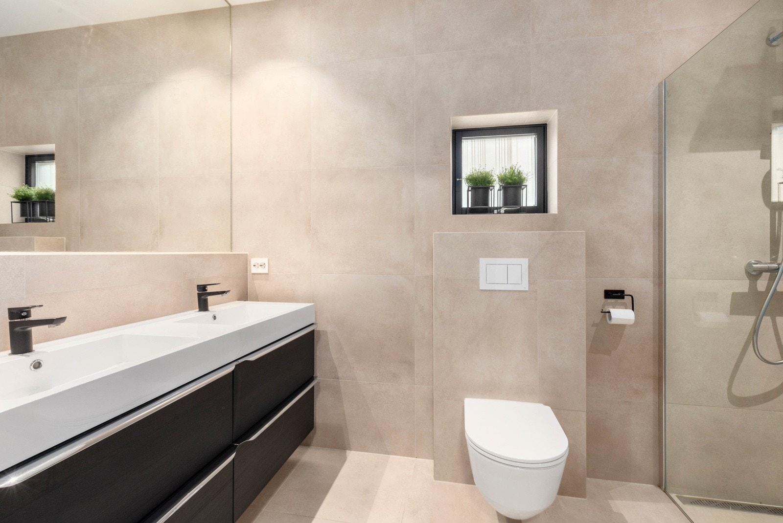 Badet er utstyrt med vegghengt toalett, baderomsinnredning og dusjhjørne Galleribilde