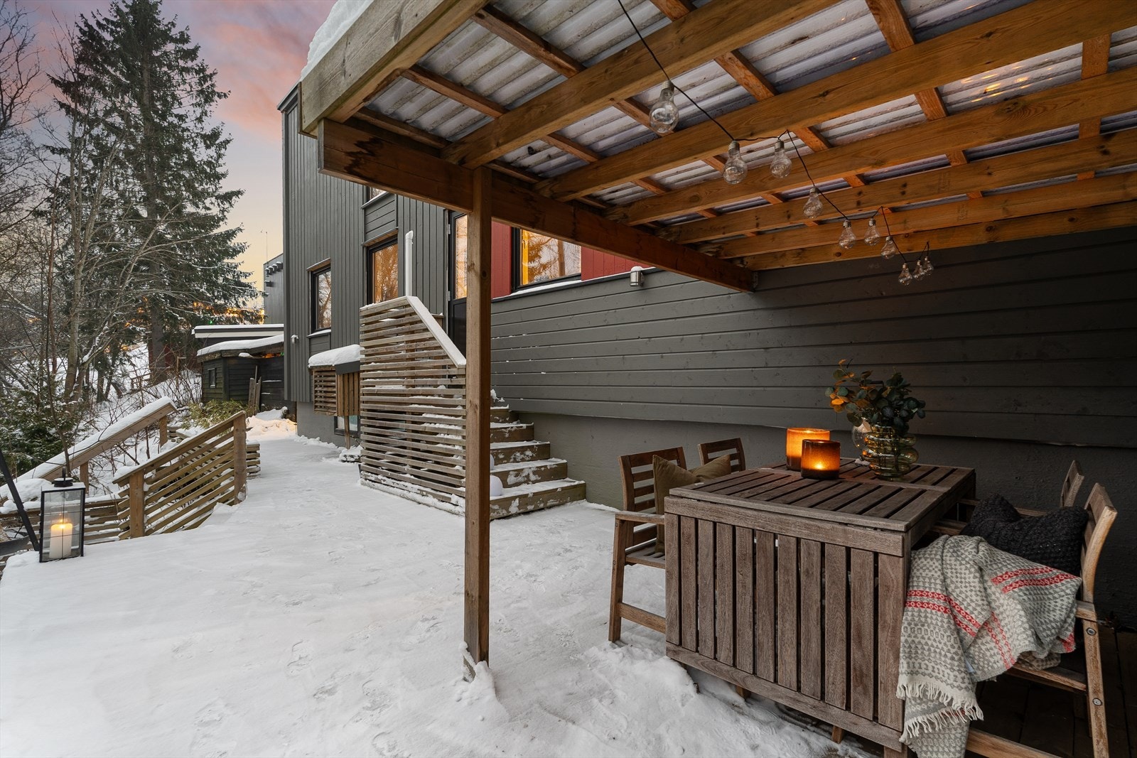 På baksiden av huset finner man en flott uteplass på 40 m² som fordeler seg over to plan. Uteplassen vender mot grøntareal og oppleves som skjermet med lite innsyn. Et overbygg omkranser sittegruppen og gjør uteplassen til et hyggelig sted for alle. Galleribilde