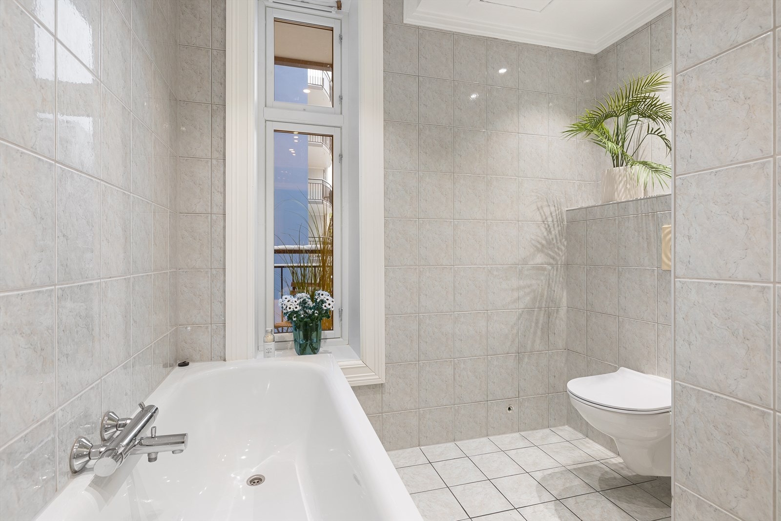 Rommet er utstyrt med badekar, dusjnisje med ny skyvedør (2025), veggmontert toalett og opplegg for vaskemaskin. Galleribilde