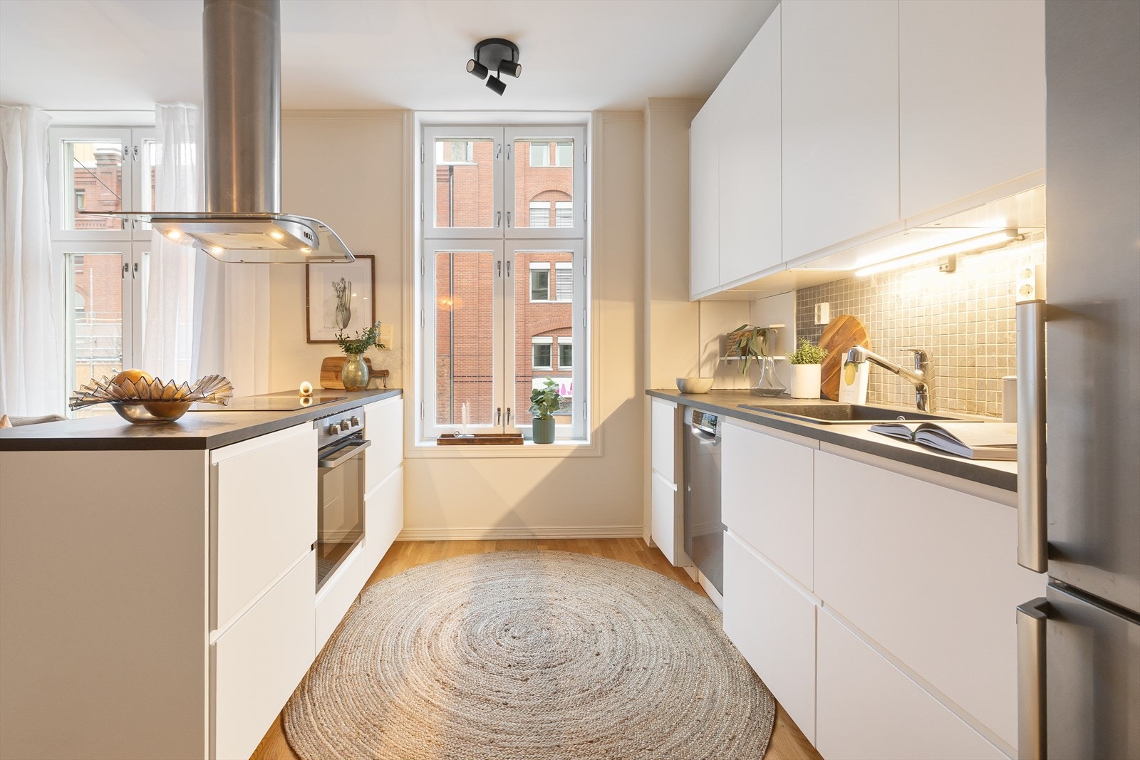 Tidsriktig innredning fra 2022 med glatte fronter, fliser på vegg over kjøkkenbenk og benkeplate i laminat. Galleribilde