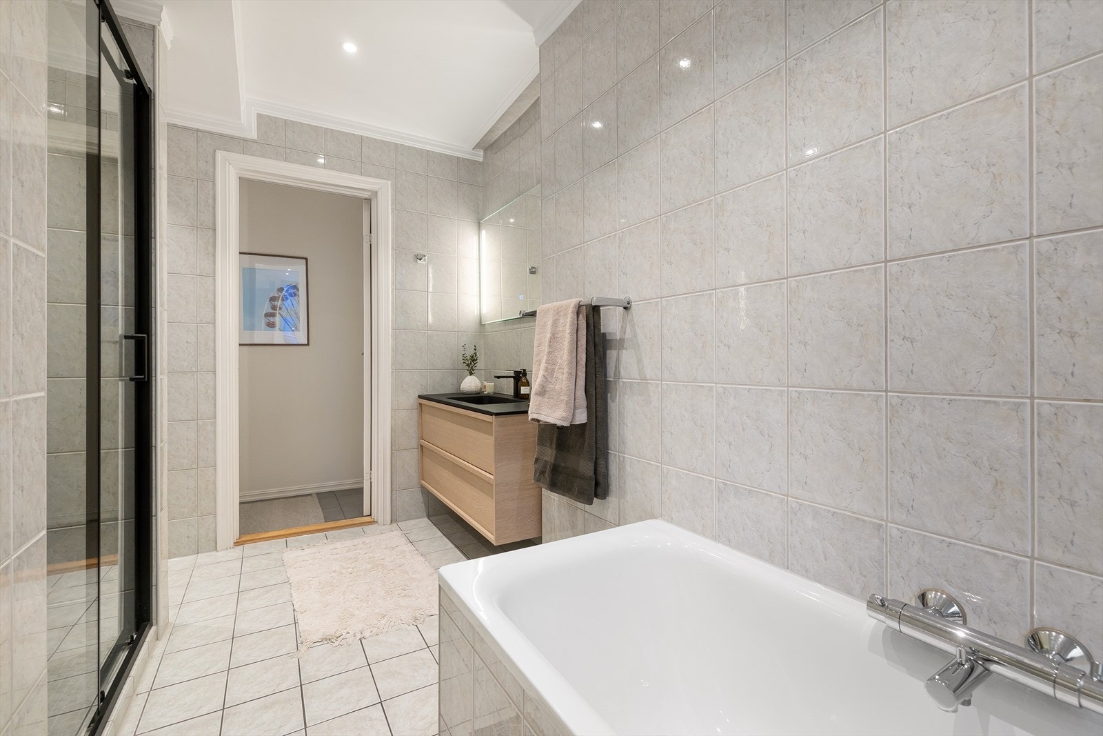 Moderne baderomsinnredning fra 2025 med skuffer, servant med ettgreps blandebatteri og speil med belysning. Galleribilde