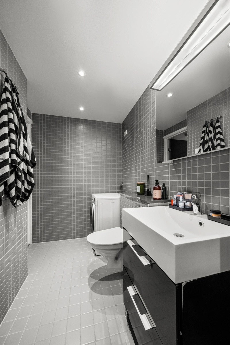 Rommet har en vegghengt servantinnredning med skuffer, speilskap, dusjhjørne, vegghengt toalett og vaskemaskin. Galleribilde