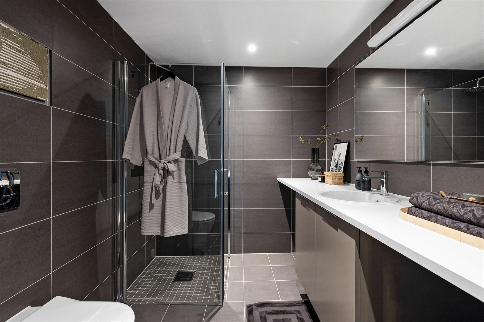 Lekkert, helfliset baderom med moderne fliser i tidsriktige farger og gulvvarme. Nedsenket himling med downlights. Galleribilde