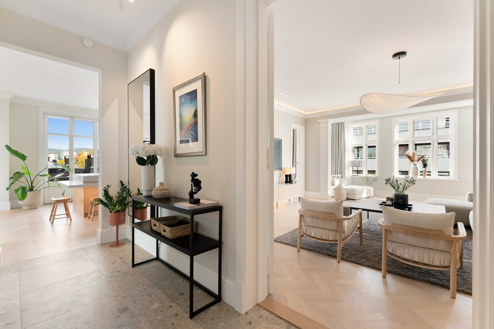 En flott hall ønsker deg velkommen hjem, med steinmønstrede, lyse storformatfliser, og fra restaurert, dobbel fløydør kommer du inn til stuen.