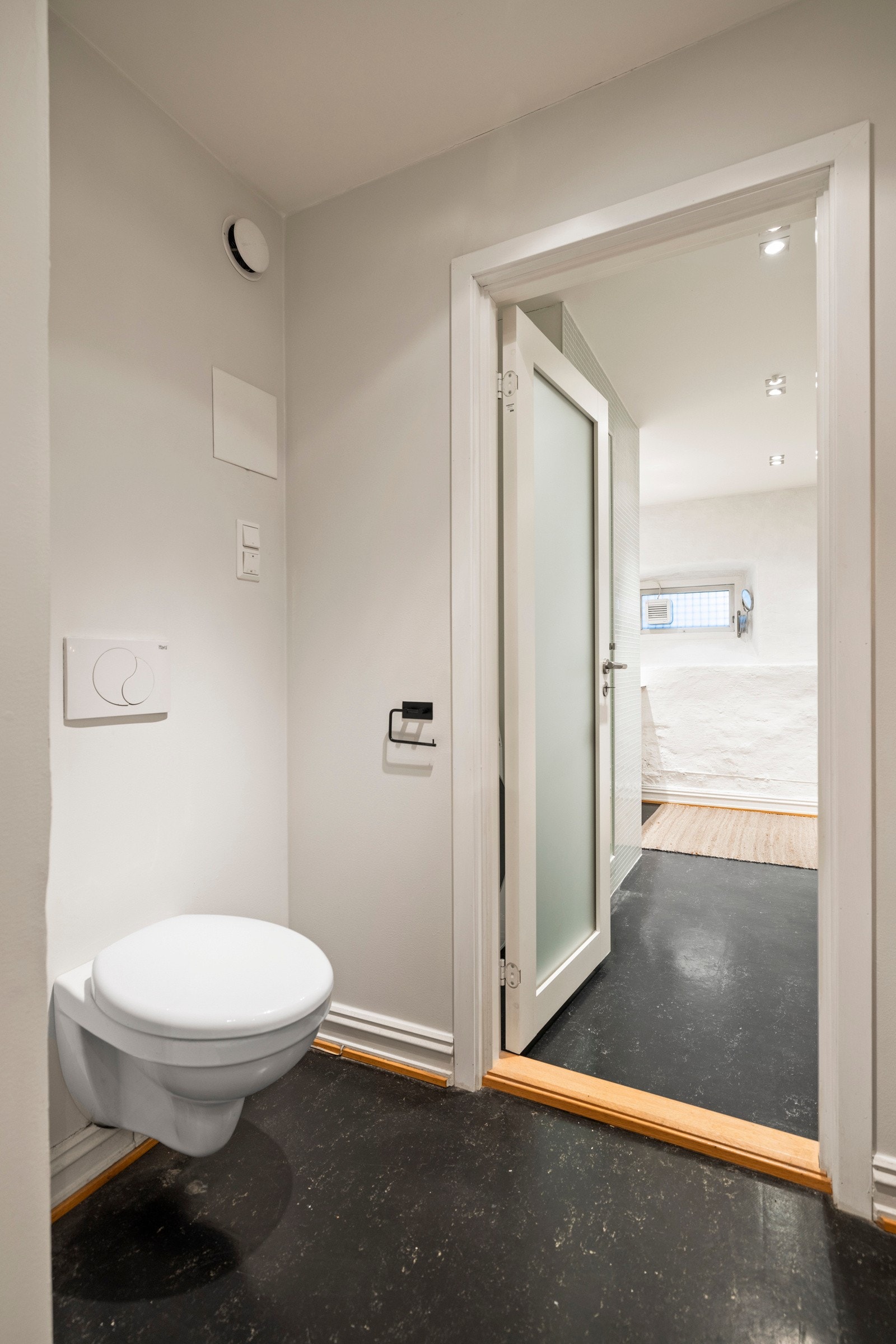 Toalettrommet med vegghengt WC, gulvbelegg, malte vegger med innslag av teglstein, samt downlights i himlingen. Mekanisk ventilasjon. Galleribilde