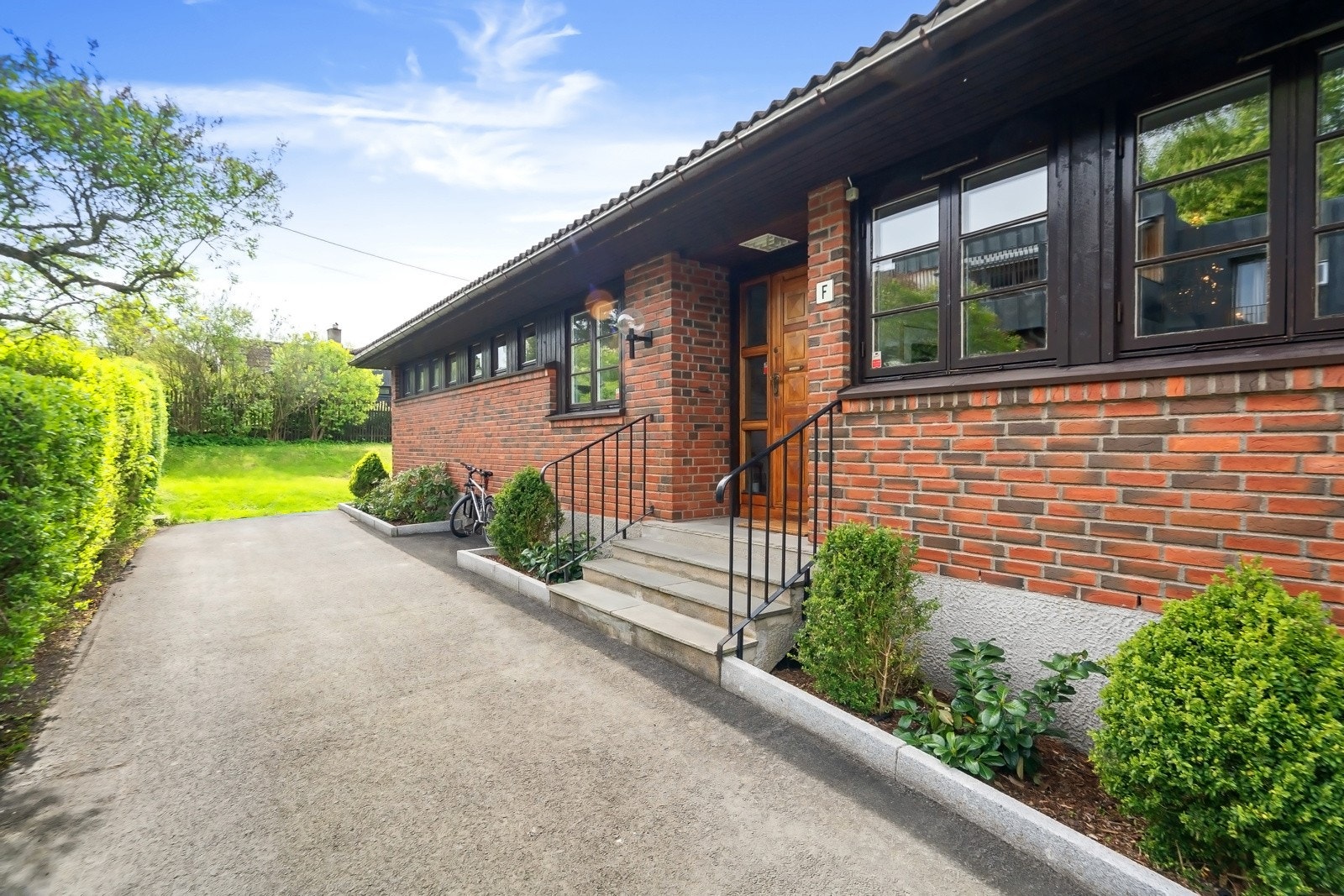 Inngangspartiet ligger mot en bilfri internvei og her finnes flere blomsterbed kantet med stein, beplantet med vintergrønt og rhododendron. Galleribilde