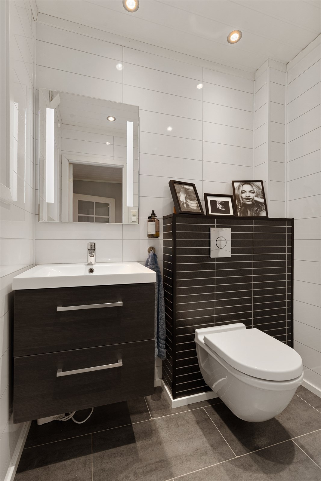 Praktisk og pent WC-rom med moderne løsninger. Rommet er utstyrt med servantskap med nedfelt servant, speil med innebygd belysning og veggmontert klosett med innebygd sisterne. Galleribilde