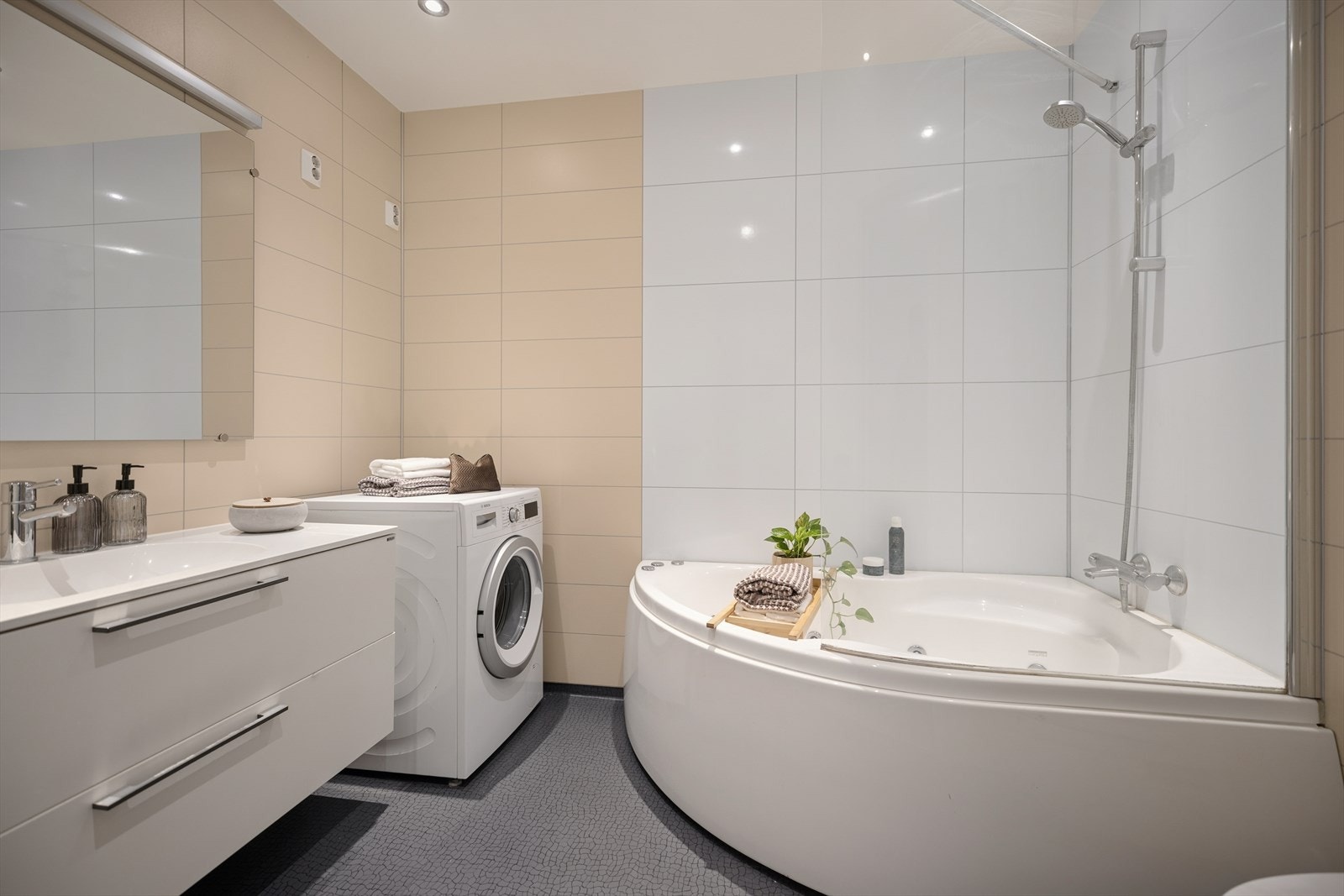 Badet er utstyrt med boblebad med dusjløsning, moderne baderomsinnredning, vegghengt toalett samt opplegg for vaskemaskin. Galleribilde