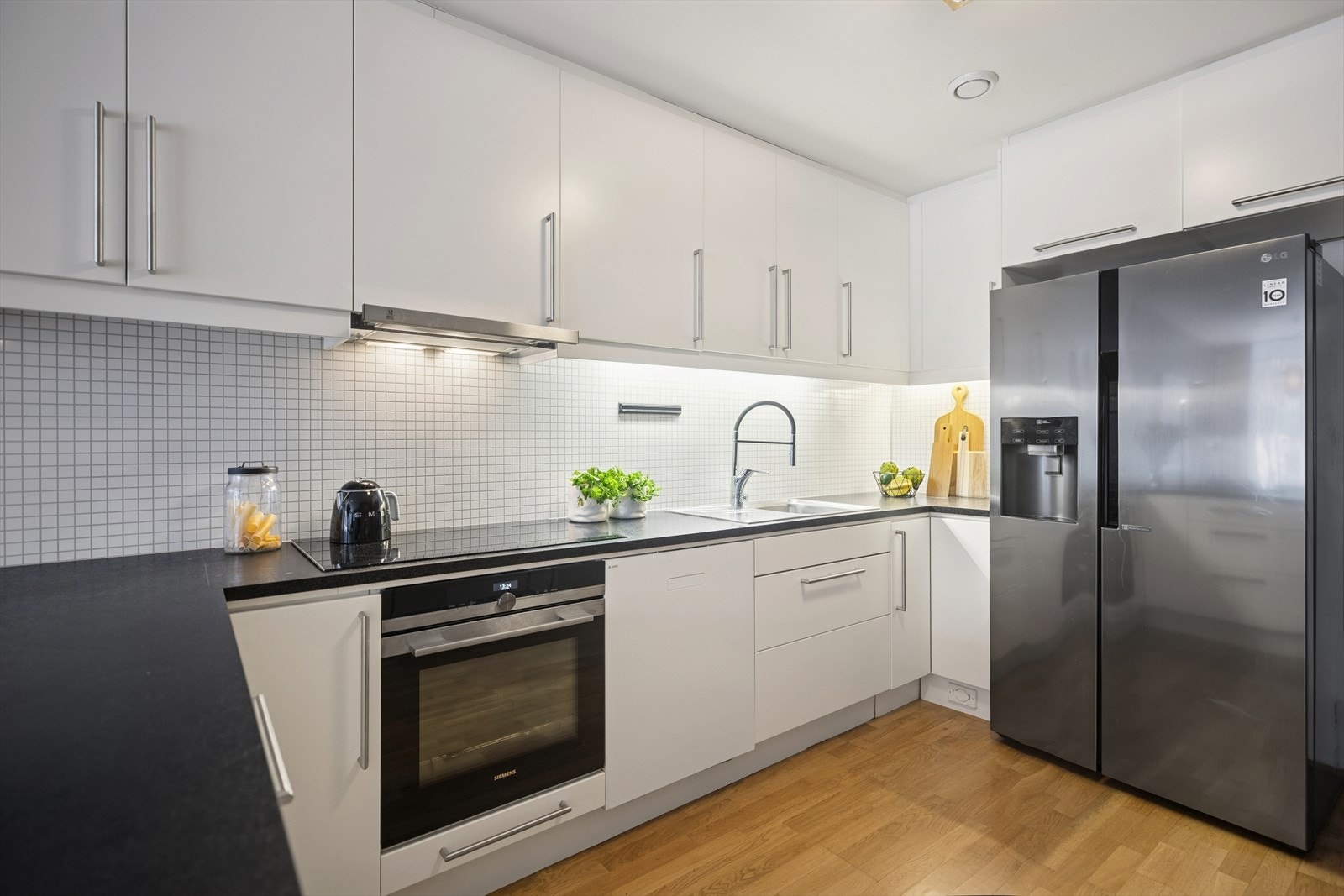 Kjøkkenet har stor benkeplass som gjør matlaging enkelt og hyggelig, med elegant flisbelagt backsplash som gir stilfullt preg. Galleribilde