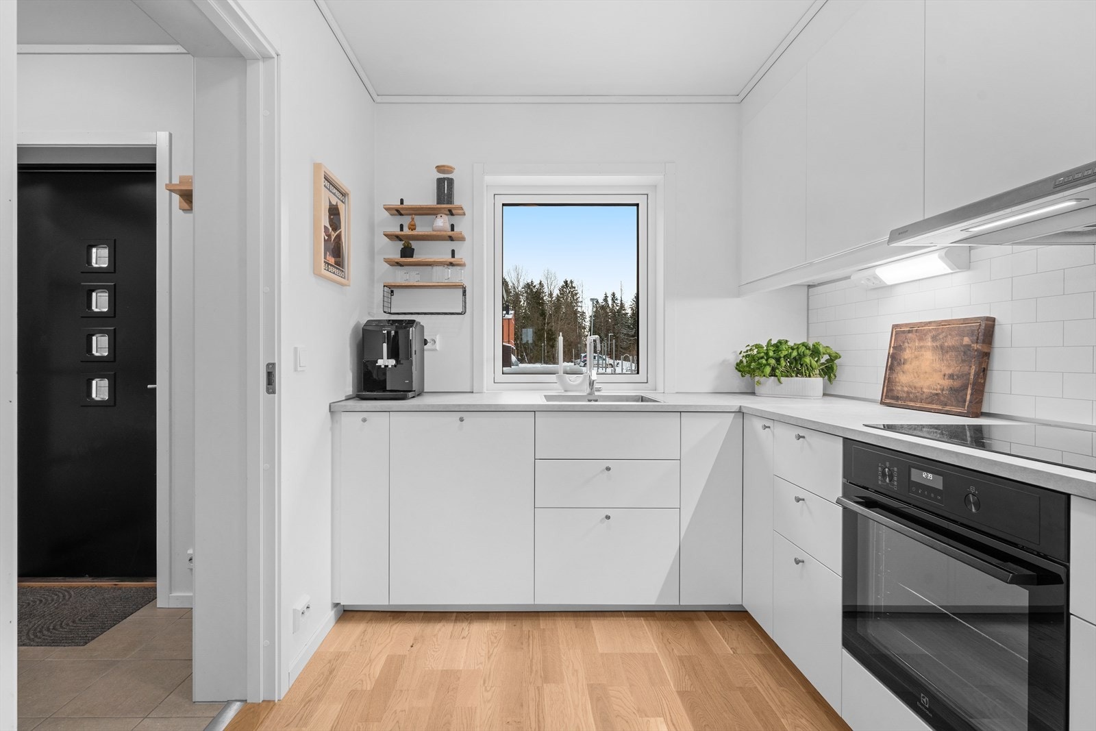 Kjøkkenet har en moderne innredning med hvite, glatte fronter og integrerte hvitevarer. Galleribilde