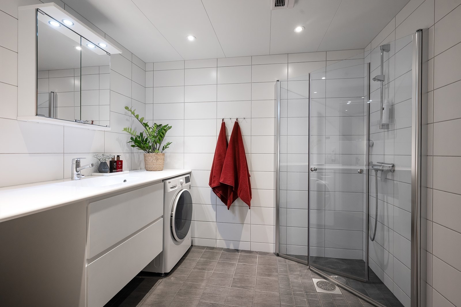 Romslig bad med vegghengt toalett, servant formstøpt i benkeplate med skuffeseksjon under, samt dusj med svingbare glassdører. Galleribilde