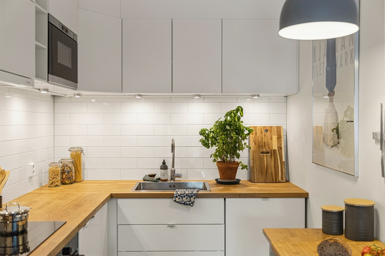 Det er flislagt over benken og montert belysning under overskapene. Galleribilde