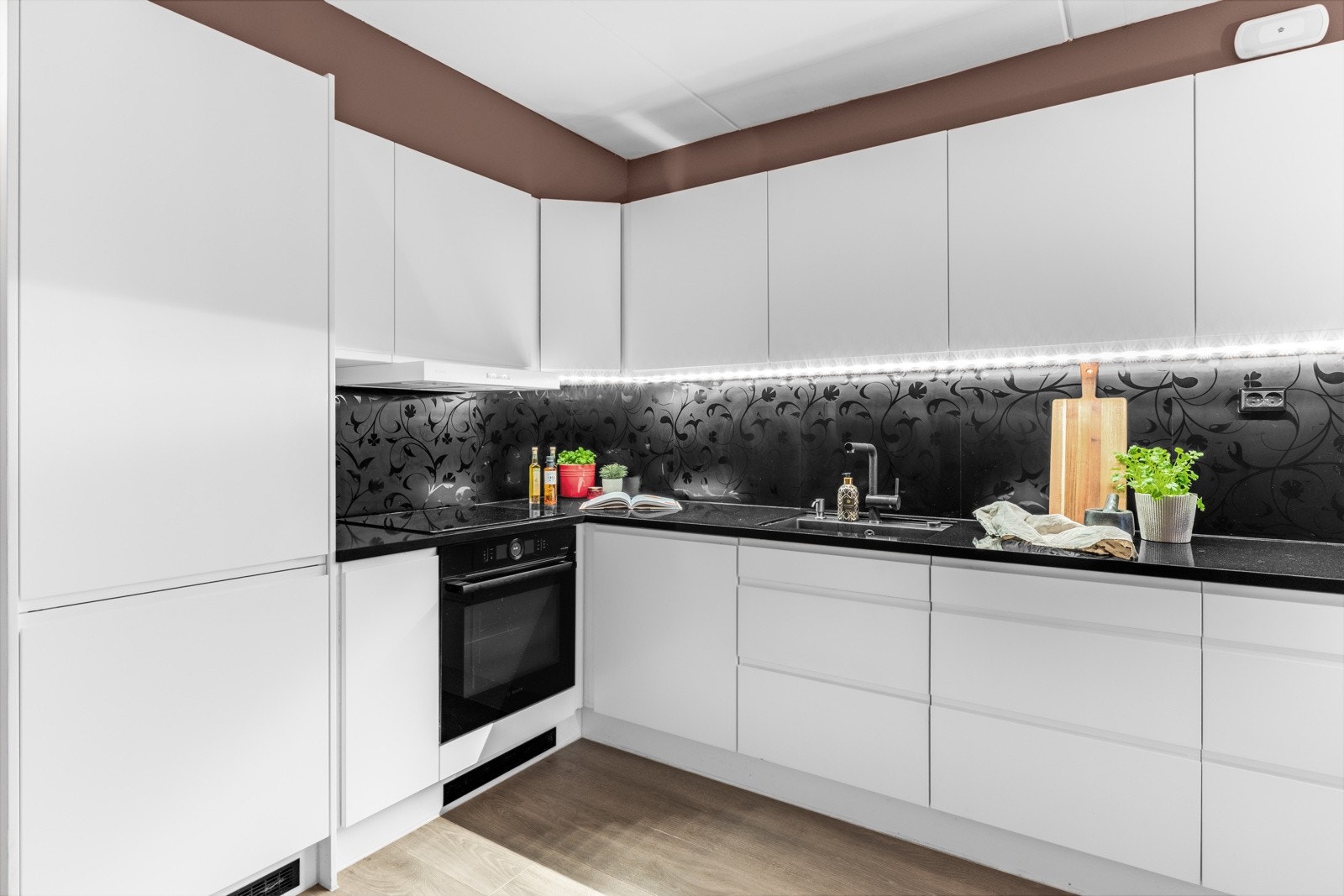 Kjøkkeninnredningen er stilren og består av hvite og håndtaksfrie fronter, benkeplate i sort, elegant stein. Galleribilde