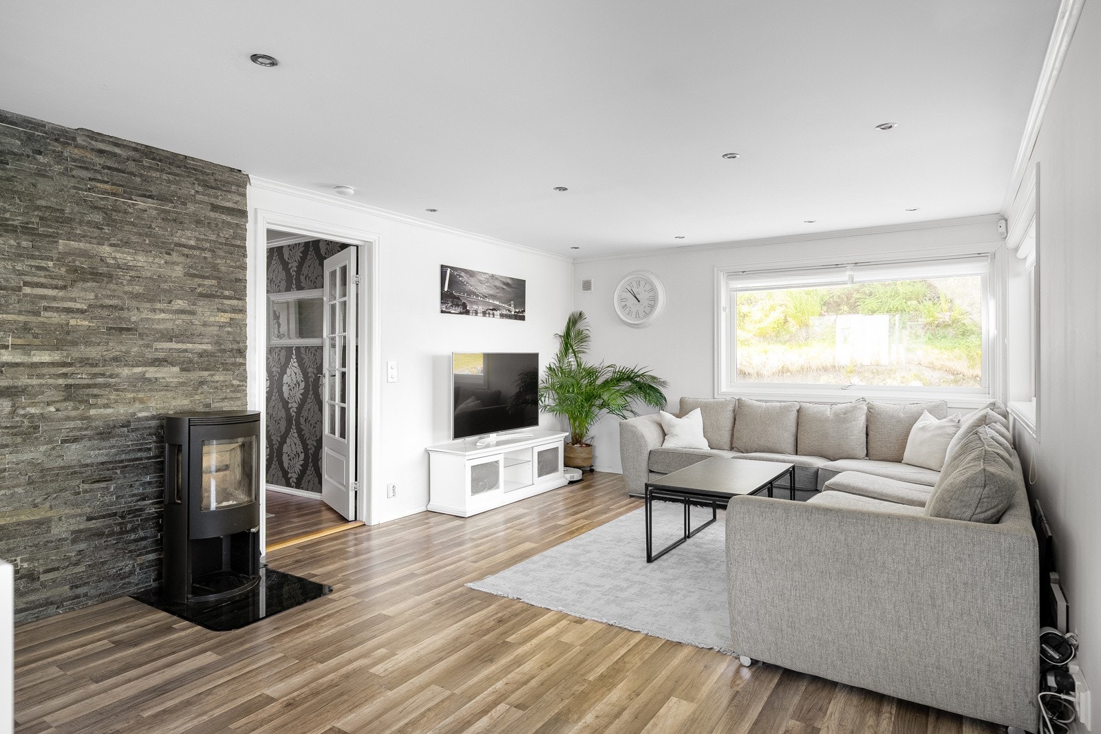 Stuen er lys og romslig, med laminatgulv og malte gipsvegger som gir en praktisk og nøytral base for ulike innredningsmuligheter. Galleribilde