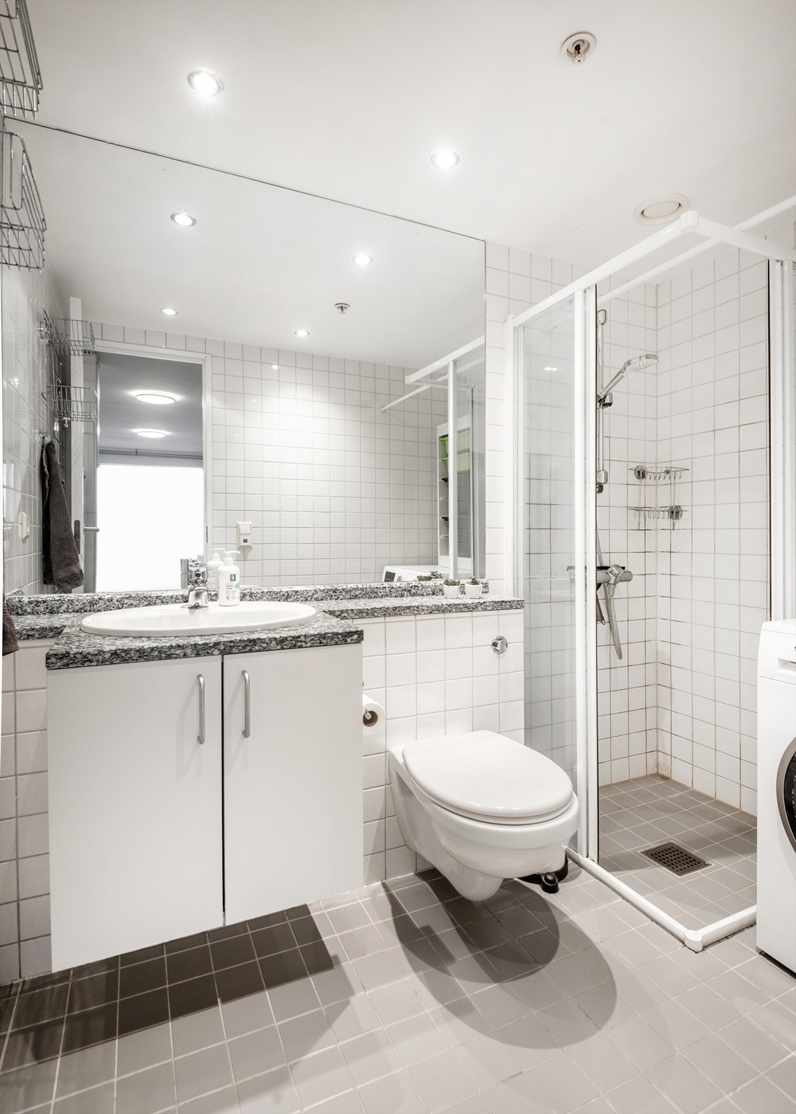 Flislagt og lyst bad med oppbevaringsmuligheter i skap under servant. Galleribilde