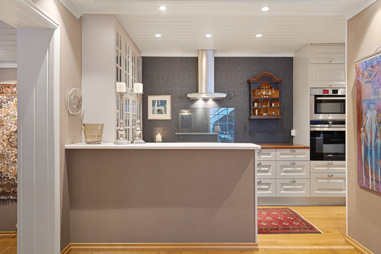 Kjøkkenet har rikelig med skap- og skuffeplass, elegante vitrineskap, heltre benkeplate og integrert/innbygget hvitevarepakke med stekeovn i høyde Galleribilde