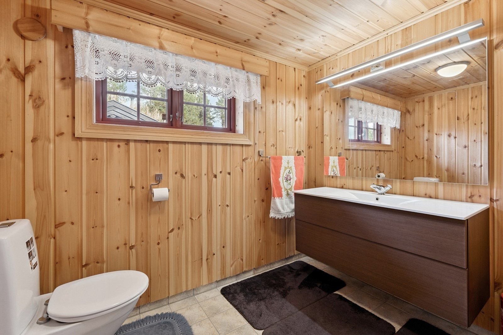 Badet er funksjonelt, og innbyr til egenpleie og avslapning. Det er innredet med stort servantskap med heldekkende servantplate, speil med tilhørende belysning, flislagt dusj og gulvmontert toalett. Galleribilde