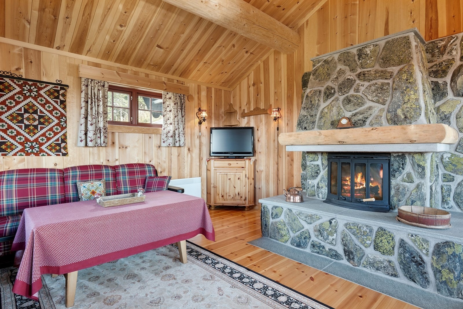 En flott plassmurt peis med innsats, forblendet med naturstein, gir en lun atmosfære og blir et naturlig samlingspunkt etter lange dager ute i naturen. Galleribilde