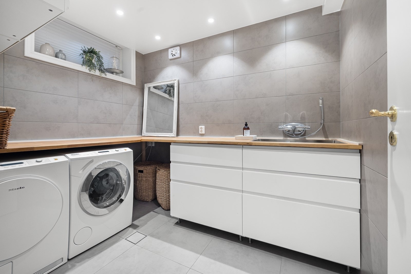 Fliselagt vaskerom, renovert i 2016, med full dokumentasjon på utført arbeid. Dimbare spotter i himling. Gulvet med varmekabler. Innredning med skuffer og utslagsvask, samt vegghengt armatur. Opplegg for vaskemaskin og tørketrommel. Veggmontert høyskap. Galleribilde