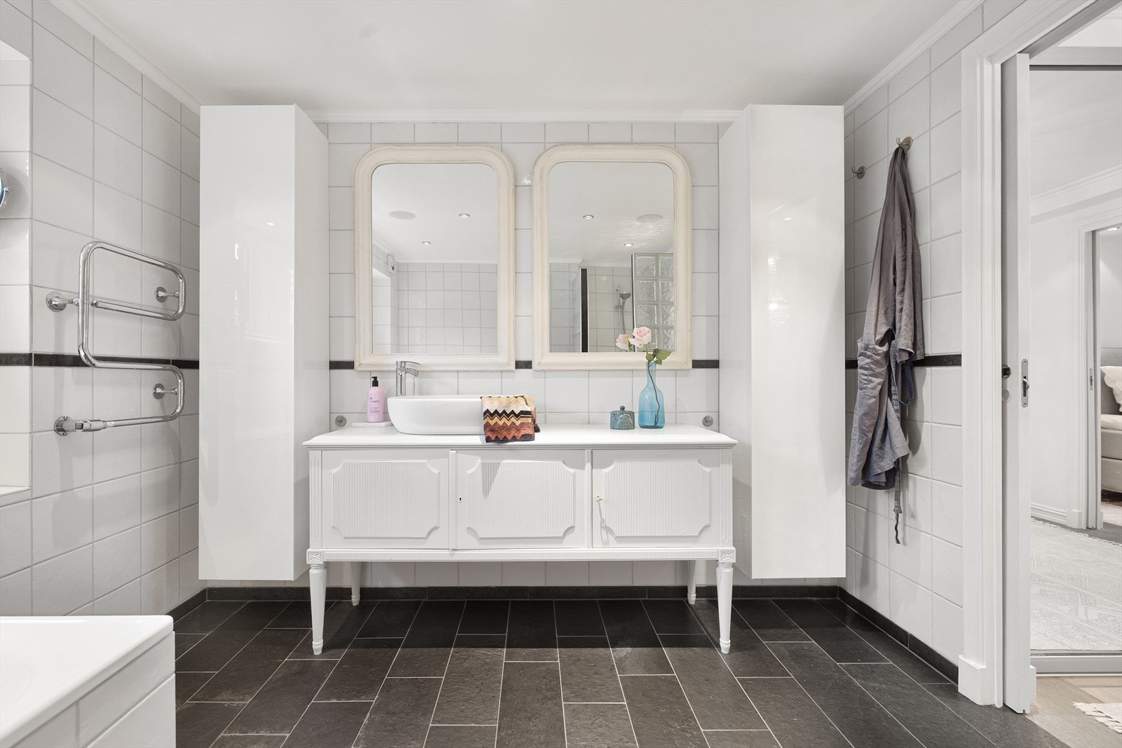 I tillegg finner man et baderomsmøbel med skapplass, toppmontert servant og ettgreps blandebatteri. Det er speil på veggen og et høyskap for ekstra oppbevaring. Galleribilde