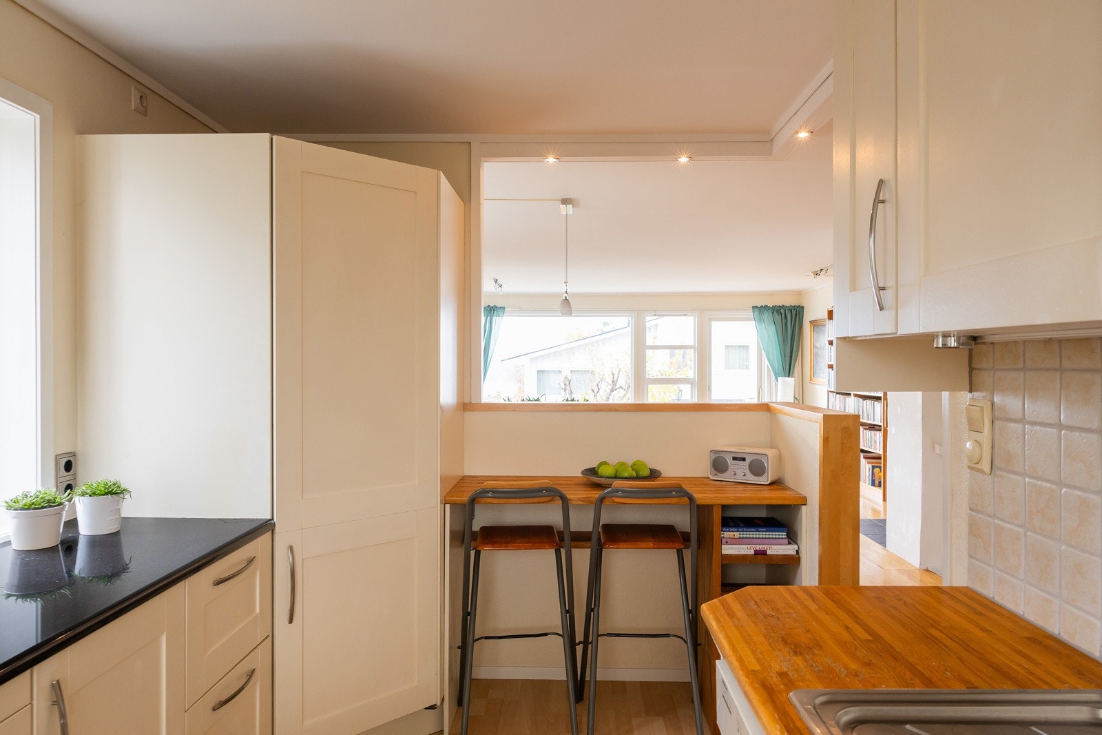 Lyst og praktisk kjøkken med hyggelig barløsning mot stue - perfekt for en kaffe eller en rask frokost Galleribilde