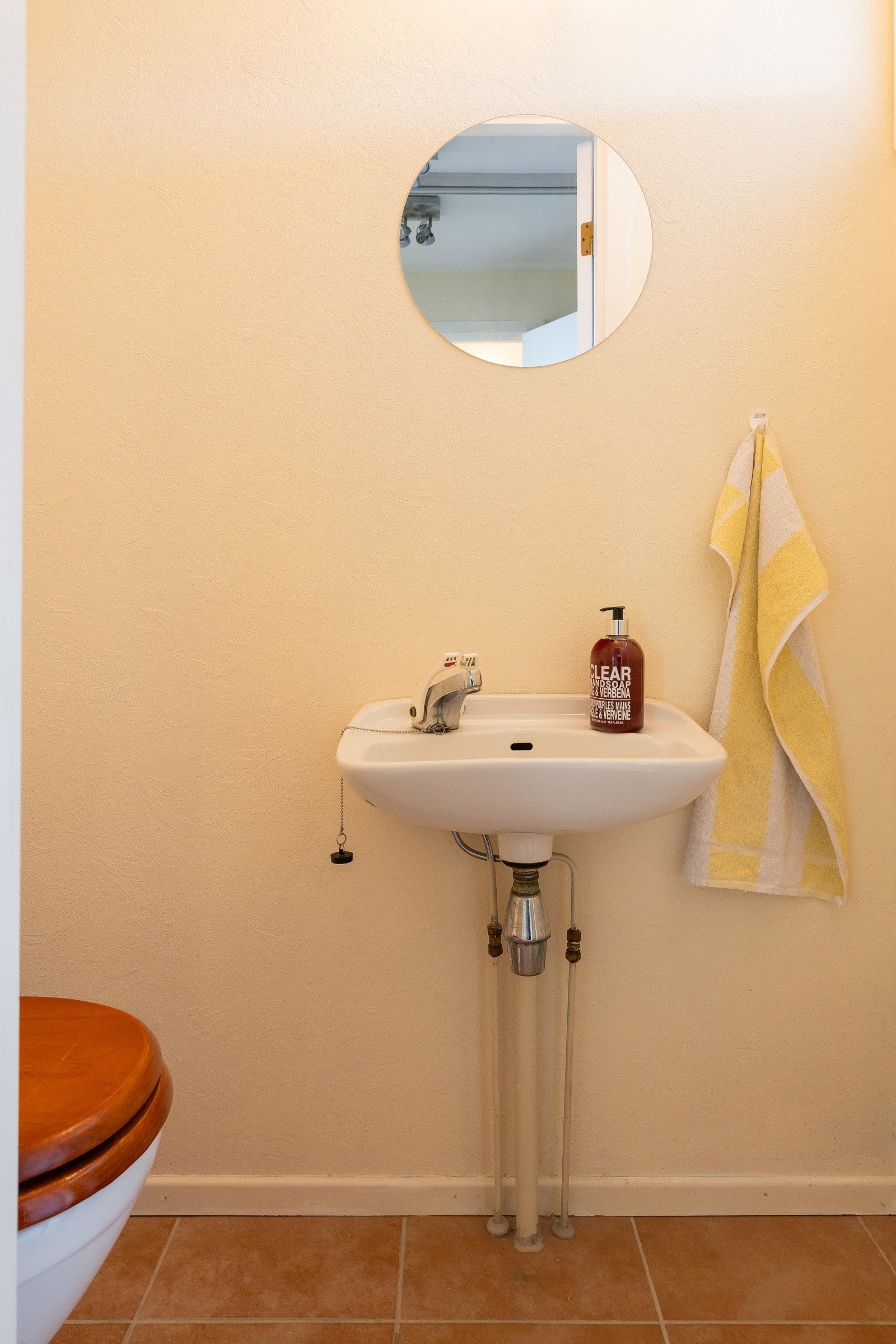 Praktisk toalettrom i tilknytning til entréen, utstyrt med gulvstående toalett og vegghengt servant. Det er flislagt gulv med varmekabler Galleribilde