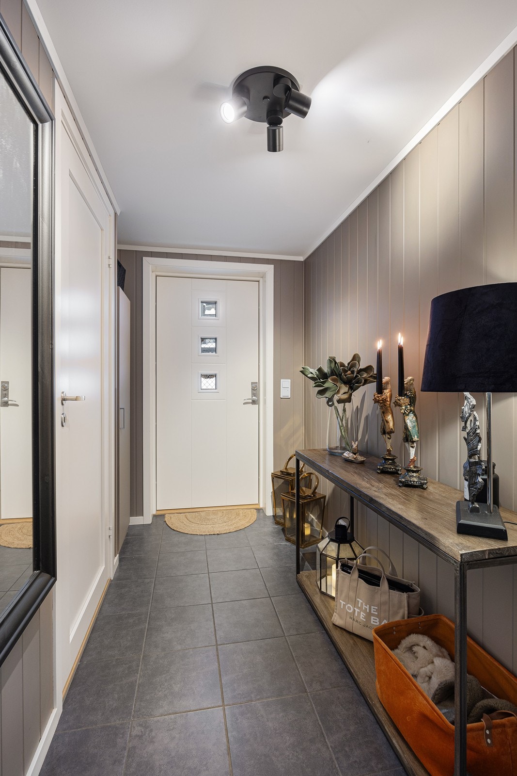 Entreen har varme under mørke fliser på gulvet. Veggene er kledd med beige panelplater. Galleribilde