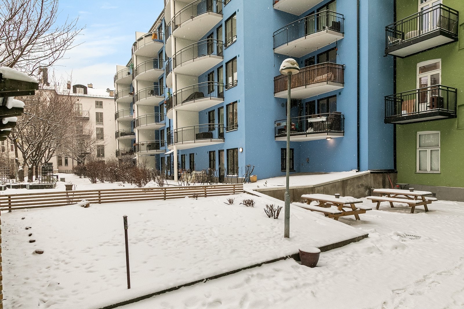 Fra gårdsplassen er det utsikt mot en bygård med balkonger og fargerike fasader. Galleribilde