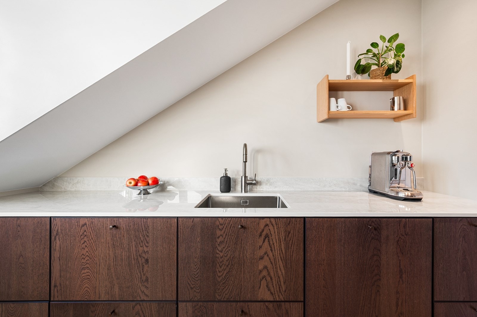 Innredningen har glatte fronter og benkeplate i kvarts med underlimt oppvaskkum og platetopp Galleribilde