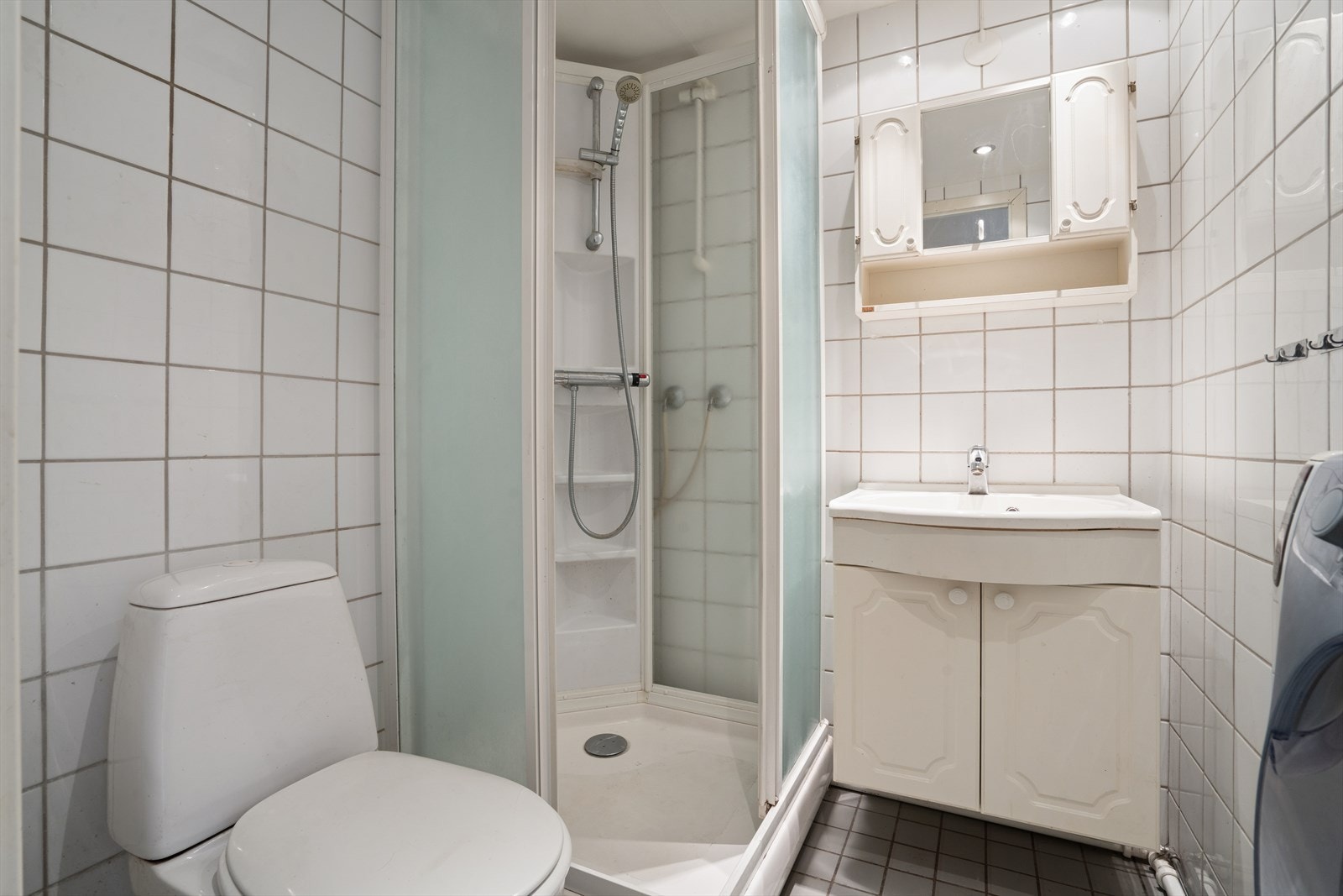 Flislagt bad innredet med dusjkabinett, toalett samt heldekkende servant Galleribilde