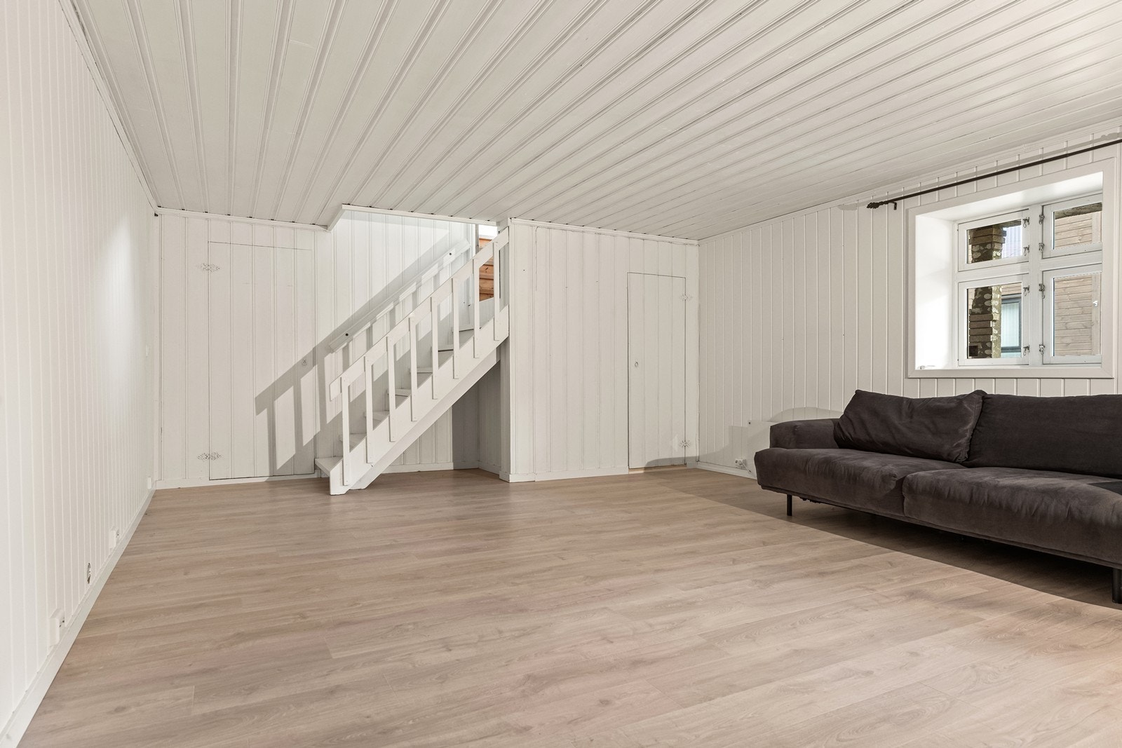 Tretrappen fra stuen leder ned til et stort, innredet rom i underetasjen. Galleribilde