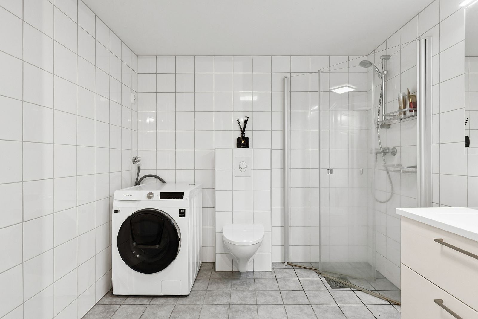 Romslig, flislagt bad med vegghengt toalett og opplegg for vaskemaskin. Galleribilde