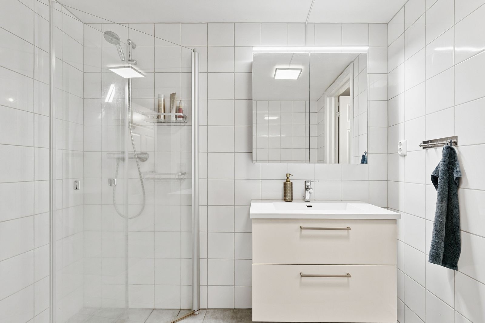 Badet er utstyrt med dusjhjørne og en servantinnredning med speilskap og belysning. Galleribilde