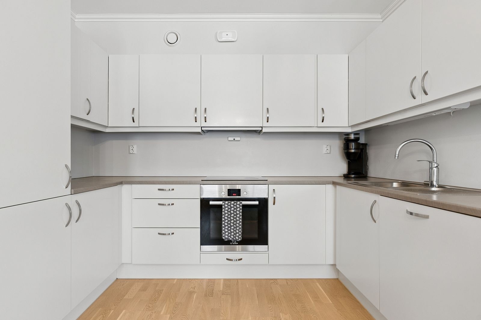 Kjøkkeninnredningen i vinkel utnytter plassen godt og gir rikelig med skap- og benkeplass. Galleribilde