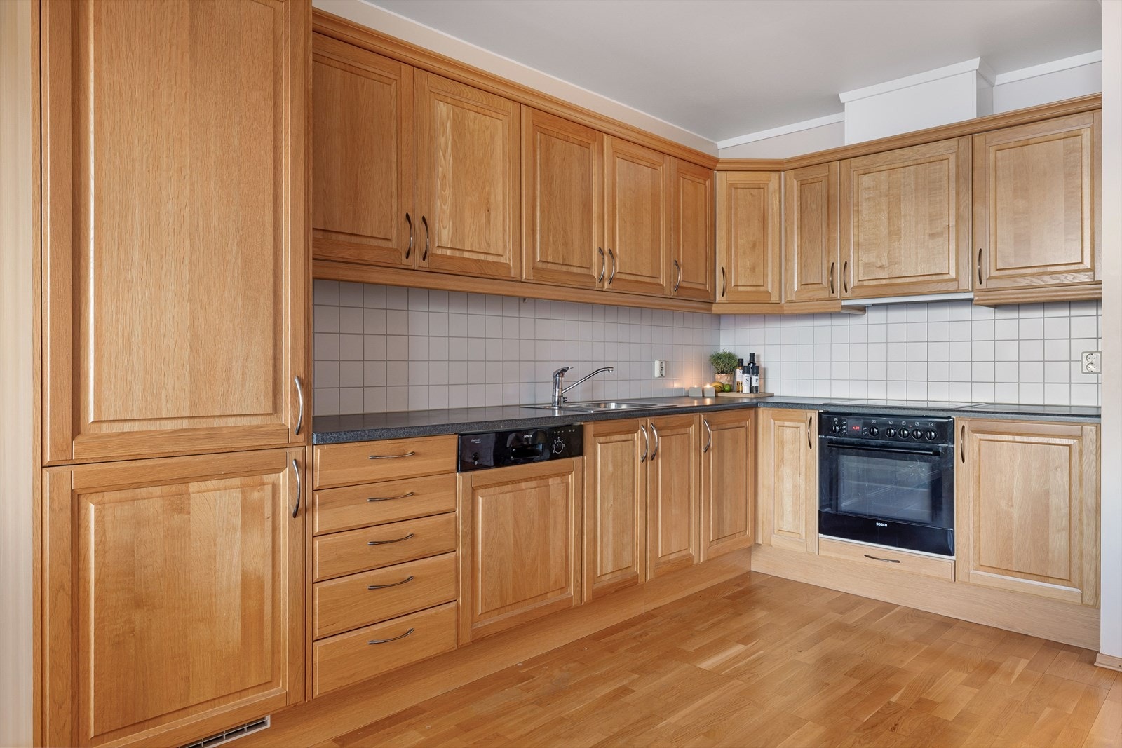 Tidløs kjøkkeninnredning fra 2006 med god skap- og benkeplass. Innredningen har profilerte fronter og laminert benkeplate med nedfelt oppvaskkum. Praktisk med lyse fliser i benkeryggen. Galleribilde